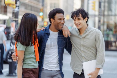 Téléchargez les photos : Groupe de jeunes multiraciaux parlant dans la rue près du campus universitaire, souriant. Jeunes étudiants planifiant le démarrage ensemble, concept d'éducation - en image libre de droit