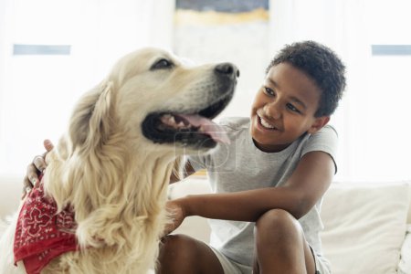 Téléchargez les photos : Portrait de garçon souriant caressant et jouant avec le chien golden retriever, meilleur ami à la maison. Pet love concept - en image libre de droit