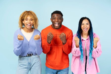 Téléchargez les photos : Groupe d'amis afro-américains heureux portant élégant succès de célébration de vêtements colorés isolés sur fond bleu. Bonnes nouvelles concept - en image libre de droit