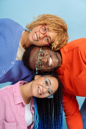 Photo for Group of smiling stylish African American friends wearing colorful glasses isolated on blue background. Happy fashion models with trendy hairstyle looking at camera posing for pictures in studio - Royalty Free Image