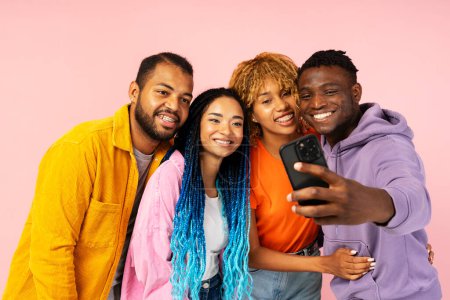 Photo for Smiling positive diverse African American friends, posing, taking selfie together, holding mobile phone, using smartphone isolated on pink background. Technology concept - Royalty Free Image