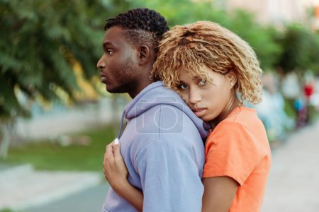 Téléchargez les photos : Portrait de jeune couple afro-américain amoureux, homme et femme étreignant en regardant la caméra dans la rue à l'extérieur. Concept d'amour, relation - en image libre de droit