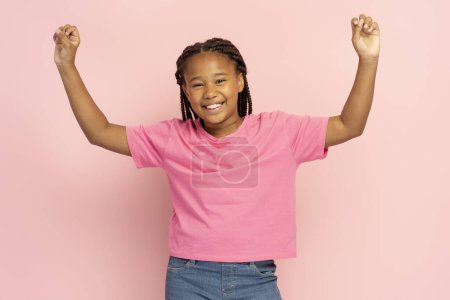 Photo for Pretty smiling Nigerian girl with stylish dreadlocks wearing casual clothes hands up, having fun, celebration looking at camera isolated on pink background. Cute kid, happy childhood concept - Royalty Free Image