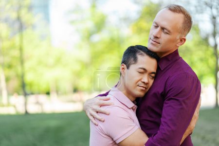 Téléchargez les photos : Portrait de couple gay d'âge moyen, hommes homosexuels étreignant les yeux fermés dans le parc, à l'extérieur, espace de copie. ? oncept de lgbt, amour, relation - en image libre de droit