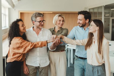 Photo for Group of successful smiling people, workers, managers holding hands together standing in modern office. Concept of teamwork, successful business - Royalty Free Image