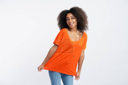 Photo for Cute smiling young woman wearing orange t shirt looking away isolated on white background. Concept of shipping, advertising, positive lifestyle - Royalty Free Image