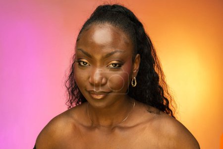 Téléchargez les photos : Gros plan portrait de jeune belle femme afro-américaine avec des cheveux élégants regardant la caméra isolée sur fond coloré. Modèle de mode attrayant posant pour des photos en studio - en image libre de droit