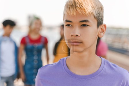 Photo for Portrait of pensive Korean teenage boy with colored hair wearing purple t shirt on the street, outdoors. Serious modern asian hipster standing in park, summer vacation. Friendship concept - Royalty Free Image
