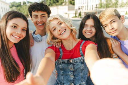 Photo for Group of smiling friends, multiracial teenagers taking selfie looking at camera on urban street. Young happy blogger influencer recording video standing together with friends. Summer concept - Royalty Free Image