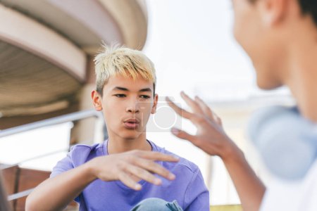 Photo for Portrait of pensive attractive Korean boy with colored hair, talking, gesturing. Stylish young hipster man wearing casual clothes on street meeting with friends. Concept of friendship, communication - Royalty Free Image