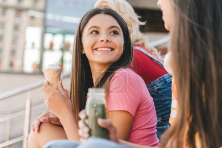 Photo for Group of happy friends, multiracial teenagers eating tasty ice cream, talking sitting on the street. Happy girls communication outdoors, having fun. Friendship, positive lifestyle, summer concept - Royalty Free Image