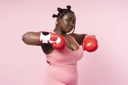 Photo for Active African american female boxer in red boxing gloves training isolated on pink background. Attractive beautiful woman doing sports, motivation, healthy lifestyle concept - Royalty Free Image
