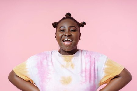 Photo for Smiling positive african woman wearing t shirt looking at camera isolated on pink background. Body positive female, summer concept - Royalty Free Image