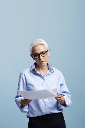 Photo for Pensive, serious, businessman wearing glasses holding business graph isolated on blue background. Female teacher working with documents - Royalty Free Image