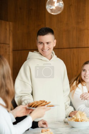 Téléchargez les photos : Vue recadrée de la femme donnant assiette avec des biscuits à l'homme collègue à la fête d'anniversaire à la maison. Concept de style de vie - en image libre de droit