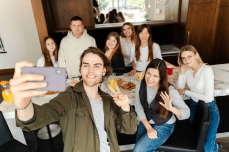 Téléchargez les photos : Groupe de jeunes prenant selfie tout en mangeant des sushis. Jeune homme tenant un smartphone, se réunissant avec des amis, assis autour lors d'une fête - en image libre de droit