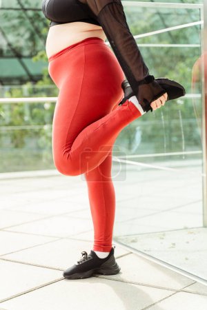 Téléchargez les photos : Photo recadrée de la femme faisant des jambes se réchauffant et s'étirant à l'extérieur. Modèle taille plus, motivation, entraînement - en image libre de droit
