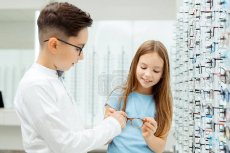 Téléchargez les photos : Des enfants portant des lunettes alors qu'ils se tenaient dans le magasin de lunettes. Concept de soins de santé - en image libre de droit