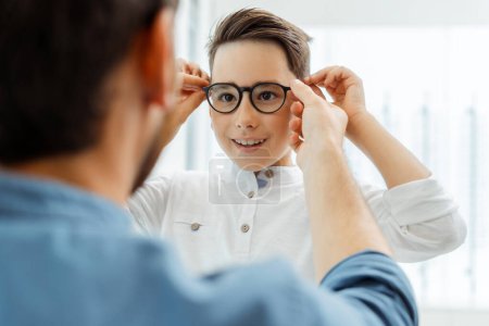 Foto de Hombre y niño eligiendo las gafas adecuadas para corregir la visión. Concepto de salud - Imagen libre de derechos