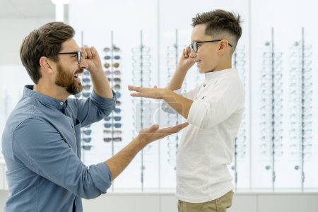 Photo for Happy man and boy wearing glasses giving five high in optical store. Health care concept - Royalty Free Image