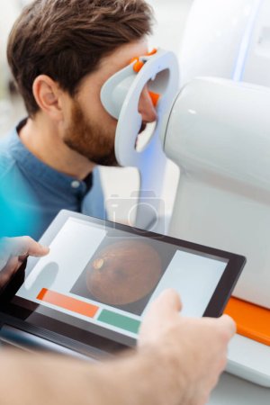 Photo for Doctor with autorefractor checking man vision at optics store. Diagnostic, health care concept - Royalty Free Image