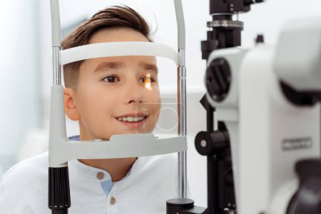 Photo for Little boy doing examination of the eyes while looking through autorefractor. Health care concept - Royalty Free Image