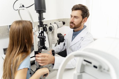 Téléchargez les photos : Un ophtalmologiste vérifie la vue d'une petite fille à la clinique. Concept de soins de santé - en image libre de droit