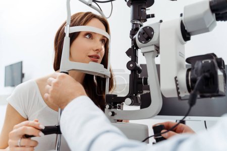 Téléchargez les photos : Ophtalmologiste examinant patiente avec un équipement ophtalmique spécial en clinique. Examen médical - en image libre de droit