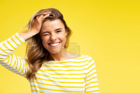 Foto de Retrato de una mujer positiva jugando con su cabello, tonteando mirando a la cámara de pie aislada sobre fondo amarillo, espacio para copiar. Concepto de modelo - Imagen libre de derechos
