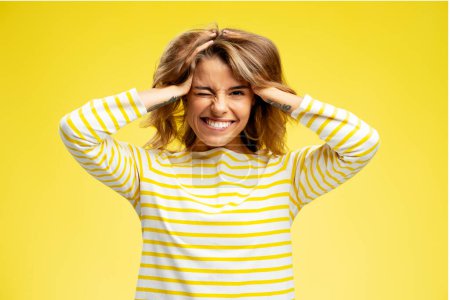 Téléchargez les photos : Portrait d'une belle femme souriante jouant avec ses cheveux, s'amusant à regarder la caméra debout isolée sur fond jaune. Concept de mannequin - en image libre de droit