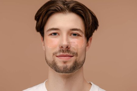 Photo for Portrait of happy man doing anti-aging skincare routine while using hydrogel eye patches. Isolated on beige background. Skin care, cosmetic, spa treatment concept - Royalty Free Image