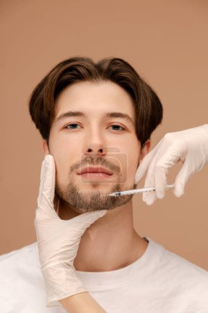 Photo for Close up of young man getting anti-aging procedure. Isolated on beige background. Beauty care, anti aging procedures, plastic surgery concept - Royalty Free Image