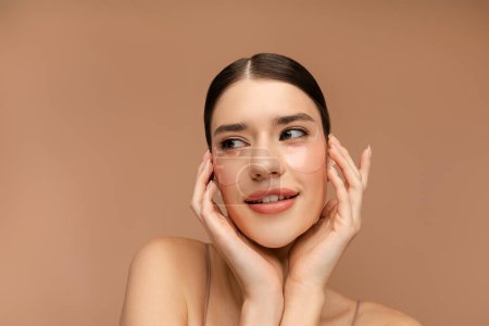 Photo for Happy young lady applying eye patches, enjoying procedures. Isolated on beige background. Skin care, natural beauty, spa treatment concept - Royalty Free Image