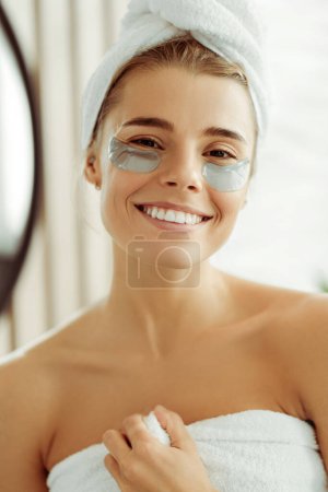 Téléchargez les photos : Portrait d'une jolie jeune femme positive avec des bandeaux oculaires en serviette blanche, regardant la caméra en gros plan, modèle de mode. Concept de soin de la peau, beauté naturelle - en image libre de droit