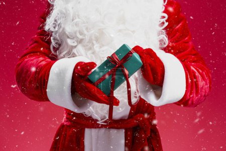Photo for Closeup Santa Claus hands holding gift box with red ribbon isolated on red background. Holiday, present, Merry Christmas concept - Royalty Free Image