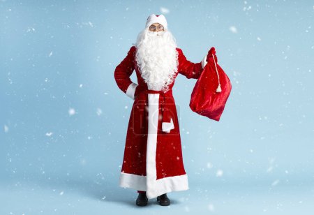 Foto de Santa Claus sosteniendo bolsa roja con regalos de Navidad aislados sobre fondo azul - Imagen libre de derechos