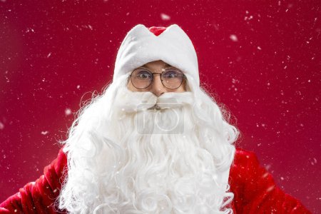 Photo for Portrait of funny Santa Claus with white beard wearing red costume looking at camera isolated on red background. Happy New Year, Christmas holiday, winter season concept - Royalty Free Image