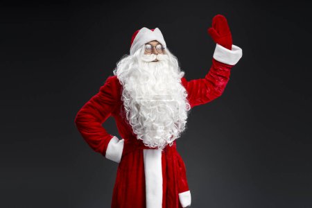 Photo for Santa Claus waving hand looking away isolated on black background. Marry Christmas, advertisement concept - Royalty Free Image
