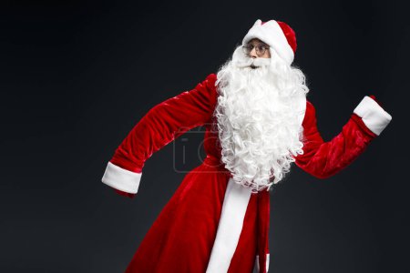 Foto de Retrato asustado emocional Santa Claus corriendo rápido aislado sobre fondo negro - Imagen libre de derechos