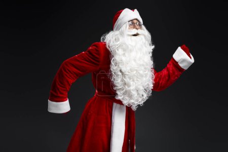 Photo for Emotional Santa Claus running, hurry up isolated on black background. Holidays, advertisement concept - Royalty Free Image