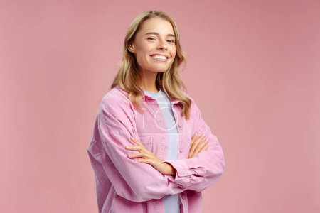 Téléchargez les photos : Portrait de femme confiante souriante, étudiante intelligente portant une chemise élégante tenant les bras croisés isolés sur fond rose - en image libre de droit
