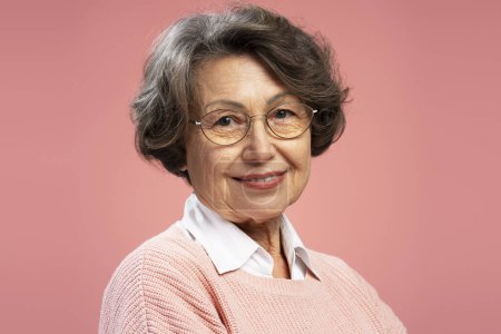 Photo for Closeup portrait smiling senior woman, cute happy grandmother wearing sweater, eyeglasses looking at camera isolated on pink background - Royalty Free Image