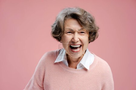 Téléchargez les photos : Portrait de sourire belle femme âgée aux cheveux gris portant des vêtements décontractés riant en regardant la caméra isolée sur fond rose. Concept de publicité, soins dentaires - en image libre de droit