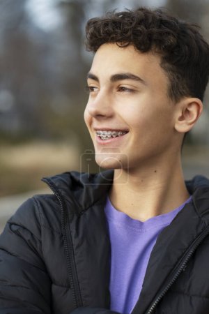 Photo for Portrait of positive happy boy, handsome teenager with braces looking away, wearing casual outfit standing on urban street. Advertisement concept, dental care - Royalty Free Image