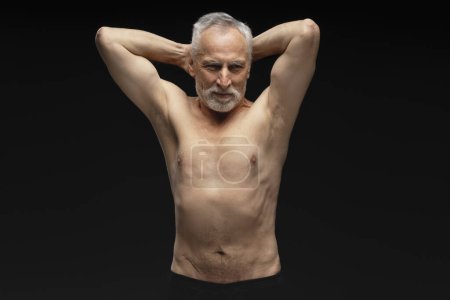 Photo for Portrait of smiling 60 years old man with naked torso showing biceps, muscular body looking at camera isolated on black background. Healthy lifestyle concept - Royalty Free Image