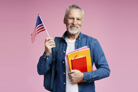 Téléchargez les photos : Portrait d'un homme âgé souriant et confiant tenant le drapeau américain isolé lors de la célébration de l'indépendance. Liberté, concept du 4 juillet - en image libre de droit
