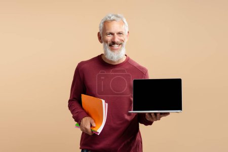 Téléchargez les photos : Beau barbu souriant homme, mature cheveux gris pigiste tenant ordinateur portable montrant écran d'ordinateur, isolé en arrière-plan. Concept d'entreprise réussi - en image libre de droit