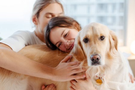 Photo for Happy happy couple hugging cute golden retriever dog sitting at cozy home. Love, friendship concept - Royalty Free Image