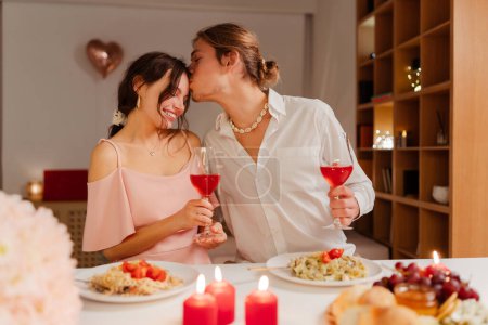 Photo for Portrait of happy romantic couple drinking wine, eating celebration Valentines day or birthday sitting in restaurant with candles. Man kissing a beautiful young woman. Dating, love, romantic dinner - Royalty Free Image