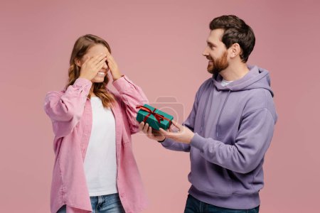Photo for Smiling man giving gift box to overjoyed beautiful woman. Portrait of happy romantic couple celebration birthday isolated on pink background. Dating, love, Valentines day - Royalty Free Image